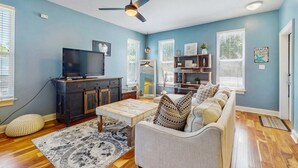 A living room with a TV, sofa, coffee table, and a ceiling fan. - Dog-friendly coastal haven with premium beach perks & resort indulgence (Santa Rosa Beach)