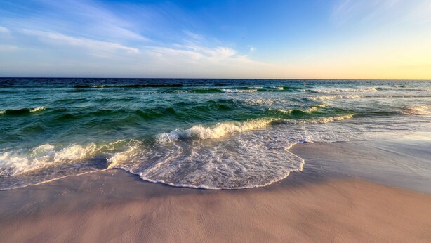 A beach with waves gently lapping onto the shore under a clear sky. - Dog-friendly coastal haven with premium beach perks & resort indulgence (Santa Rosa Beach)
