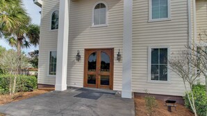 A two-story building with a symmetrical facade, featuring a central double door with glass panels, flanked by two windows on each side. - Dog-friendly coastal haven with premium beach perks & resort indulgence (Santa Rosa Beach)
