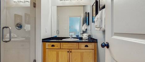 A bathroom with a shower, a sink, and a mirror.