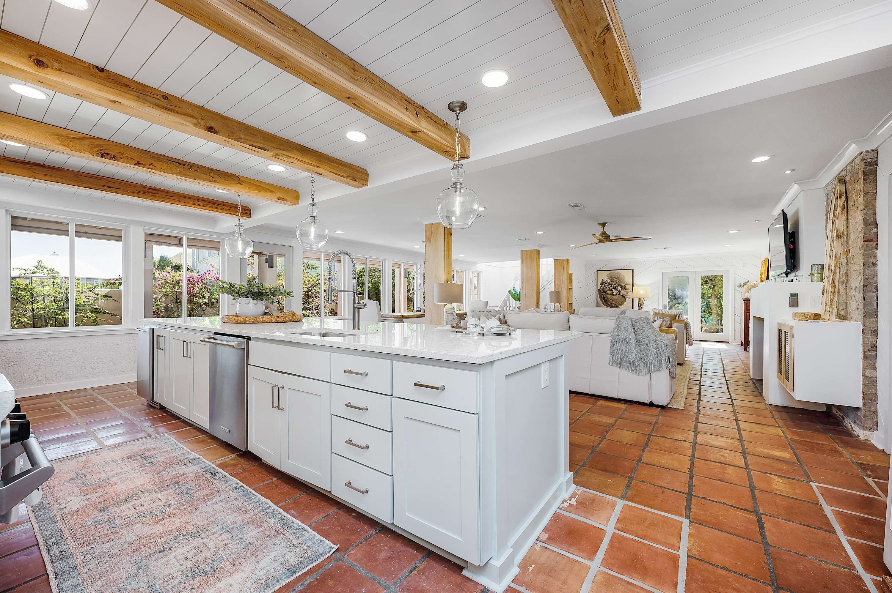 A spacious kitchen with white cabinetry, a large island, and a rustic ceiling.