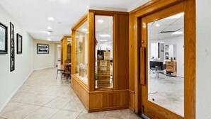 A hallway with wooden doors, framed artwork on the walls, and a tiled floor. - Beautiful Gulf-front retreat with central AC, shared pool & hot tub, free WiFi, (Miramar Beach)