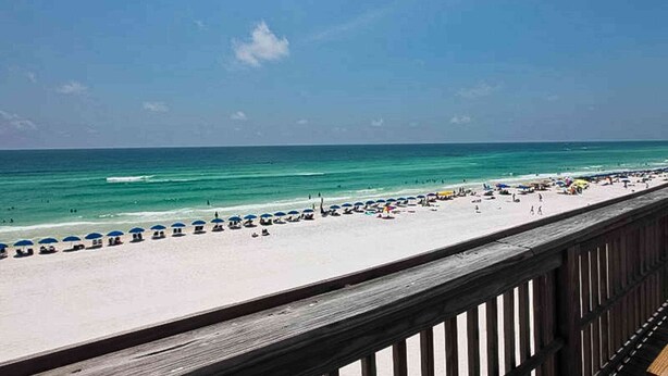 A beach with a wooden boardwalk and umbrellas. - This cozy and bright resort studio is perfect for a beach getaway. (Miramar Beach)
