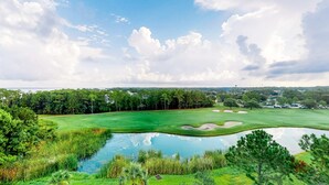 Un parcours de golf avec un étang, des arbres et un ciel dégagé.