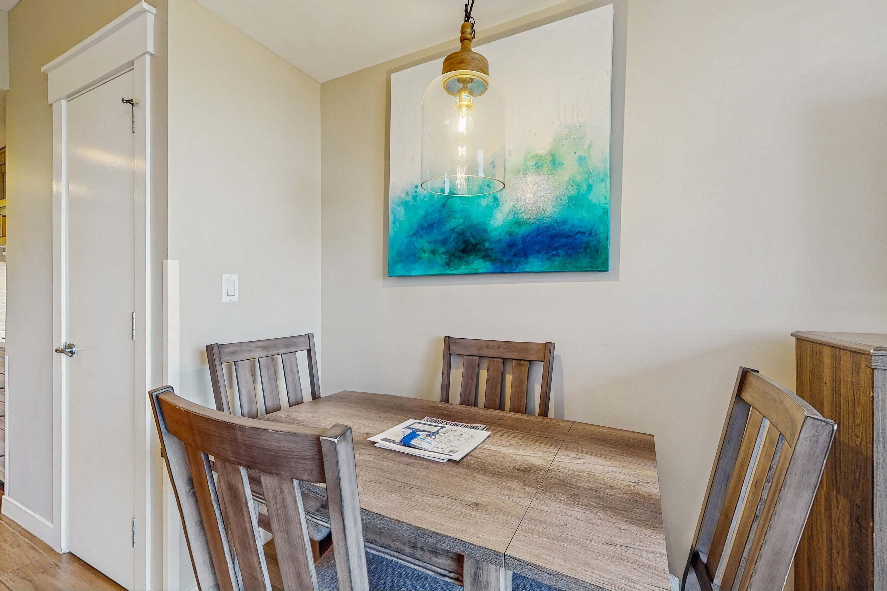 Een eetruimte met een houten tafel, vier stoelen en een hanglamp.