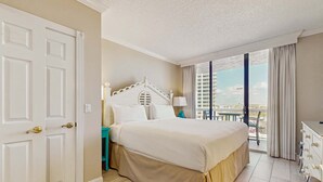 A hotel room with a bed, a nightstand, a dresser, and a balcony with a view. - Cozy condo w/ balcony, beach access & shared pool/hot tub/tennis/gym (Miramar Beach)
