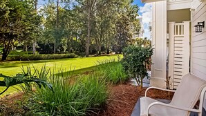 A porch with a chair, a well-maintained lawn, and trees. - LaSata beauty with patio, pools, hot tubs, fitness center, AC & beach access (Miramar Beach)