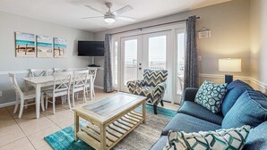 Un salon comprenant une table à manger, des chaises, un canapé, une table basse, un téléviseur et un ventilateur de plafond.