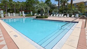 A rectangular pool with a tiled edge, surrounded by lounge chairs and palm trees. - Beachy condo with free WiFi & shared pools, hot tub - short walk to the beach (Santa Rosa Beach)