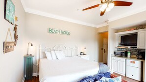 A bedroom with a bed, a ceiling fan, a kitchenette, and a sign that reads "BEACH HOUSE". - Beachy condo with free WiFi & shared pools, hot tub - short walk to the beach (Santa Rosa Beach)