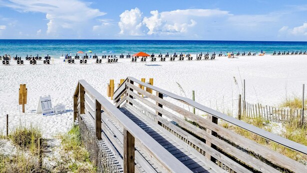A beach with a wooden boardwalk leading to the shore, white sand, and a clear blue sky. - First-floor condo with a kitchen, patio, pool, hot tub, grill, & spa access (Miramar Beach)