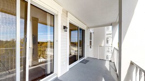 Un balcó cobert amb portes corredisses de vidre, un estriquet a la porta i una petita làmpada exterior.