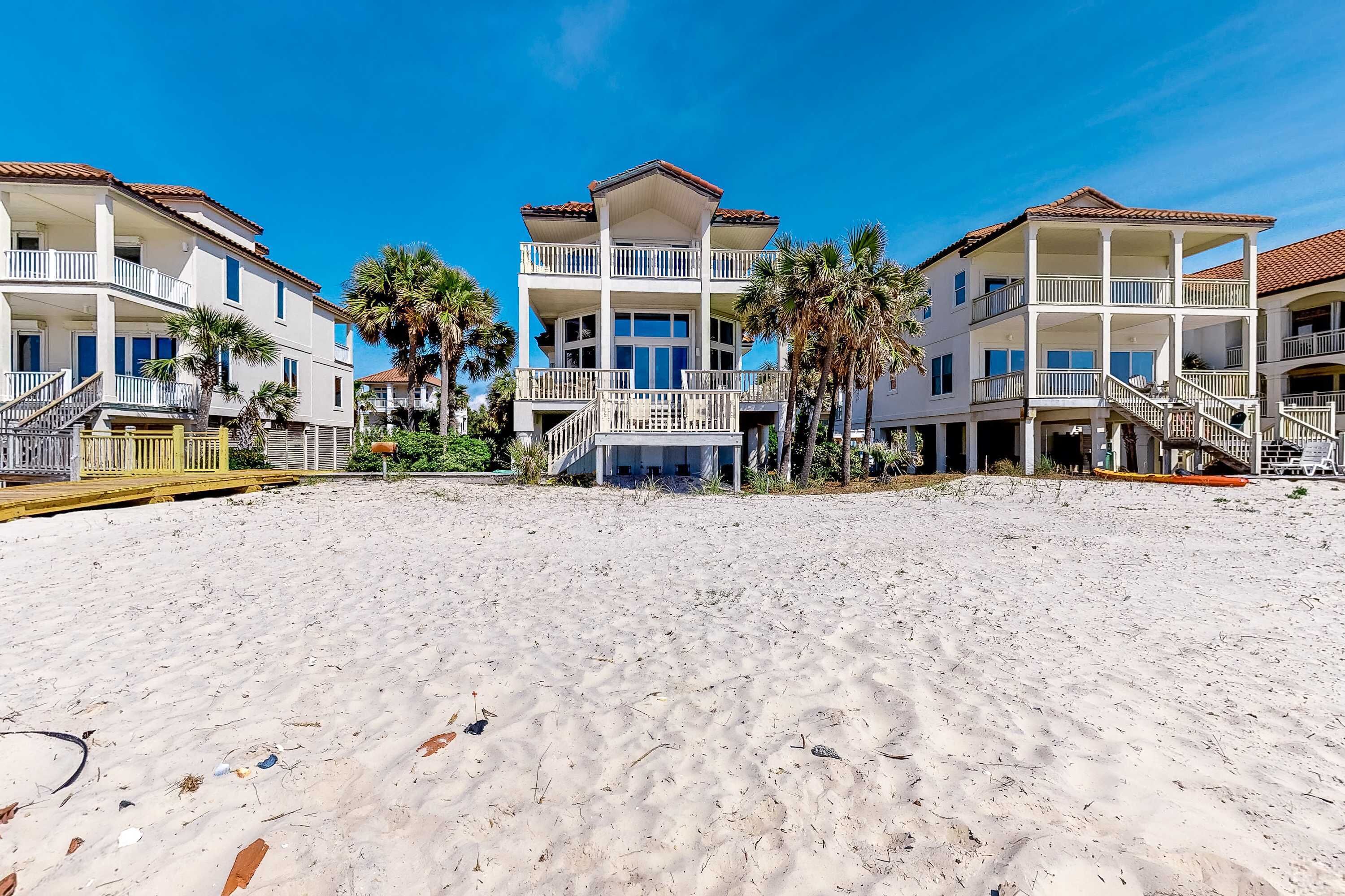 A beachfront property with multiple-story buildings, balconies, and a sandy beach.