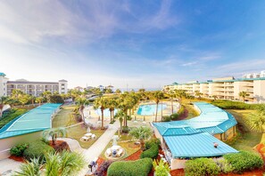 Et resort med flere swimmingpools, palmer og en klar blå himmel.