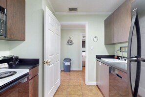 A kitchen with wooden cabinets, a stainless steel refrigerator, a stove, and a sink. - Gulf Getaway with Free WiFi, Wet Bar, Enclosed Yard, & Screened-In Porch (Port St. Joe)