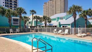 A swimming pool with a metal ladder, surrounded by palm trees and white lounge chairs. - Quaint Miramar Beach home with loft, pool, patio, full kitchen, & washer/dryer (Miramar Beach)