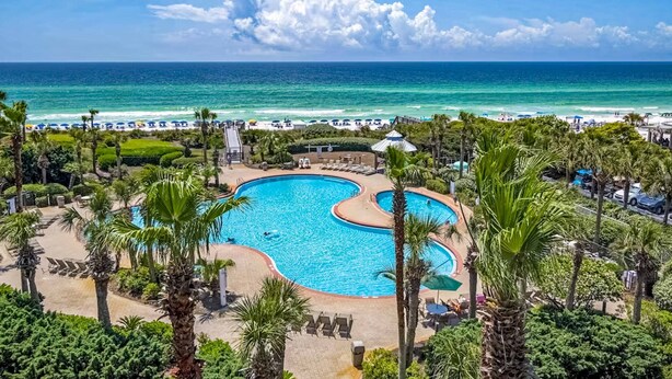 A resort with a large swimming pool, beach access, and palm trees. - Newly-renovated top-floor condo with a beach & Gulf view, lagoon pool, & hot tub (Miramar Beach)