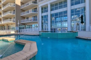 Zona de piscina de hotel con vista despejada del exterior del edificio, incluyendo balcones y ventanas amplias.