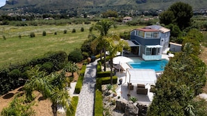 A modern house with a swimming pool, surrounded by a well-maintained garden and a mountainous backdrop. - Exclusive villa with swimming pool and spa (CASTELLAMMARE DEL GOLFO)
