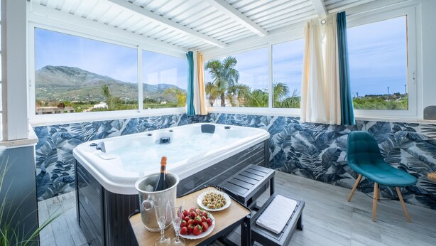 A hot tub with a mountain view, a table with drinks and snacks, and a chair. - Exclusive villa with swimming pool and spa (CASTELLAMMARE DEL GOLFO)