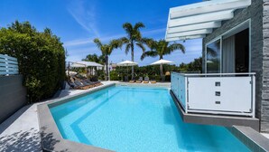A rectangular swimming pool with clear blue water, surrounded by a stone deck and a white fence. There are lounge chairs and umbrellas along the poolside. - Exclusive villa with swimming pool and spa (CASTELLAMMARE DEL GOLFO)
