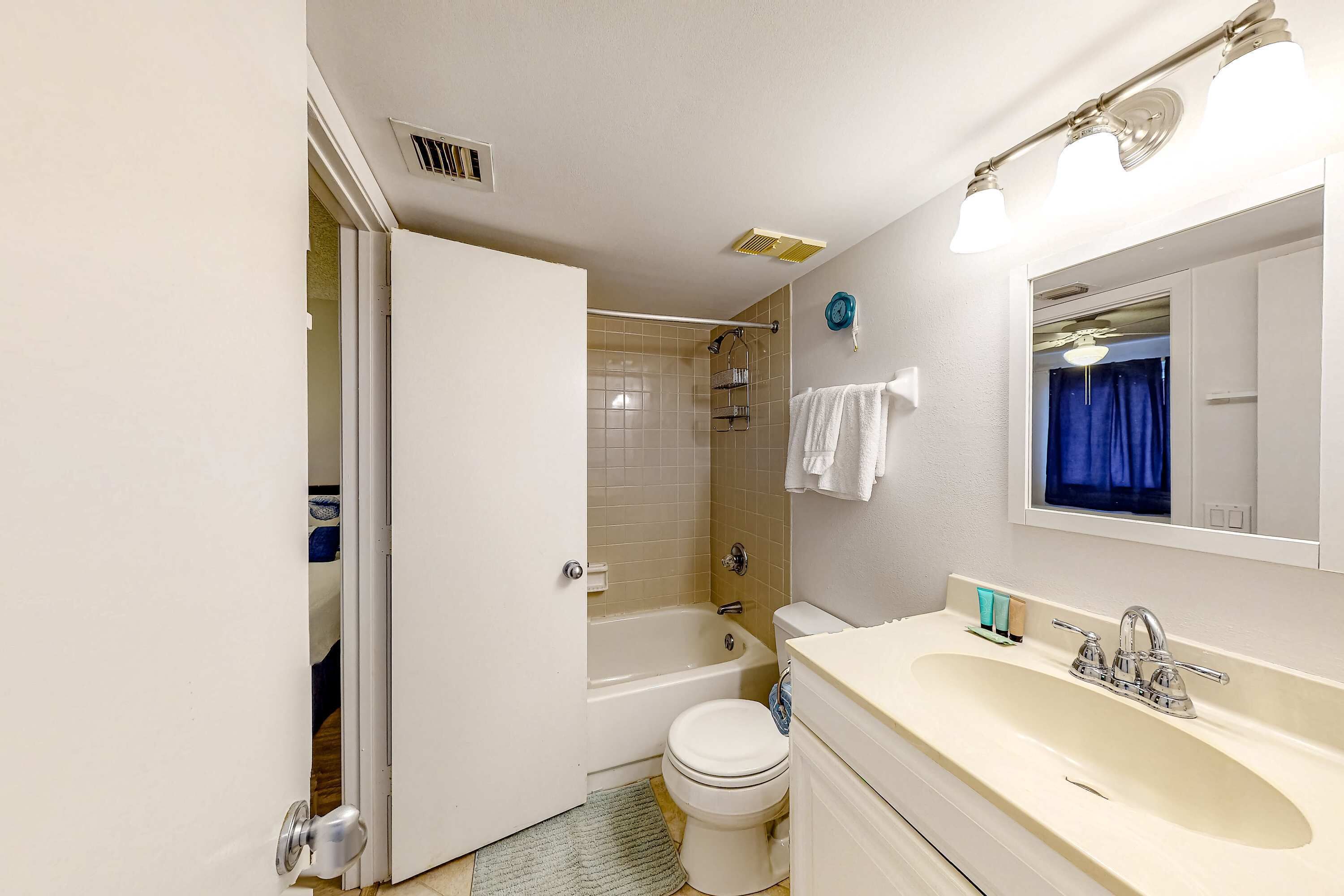 Un baño con bañera, inodoro, lavabo y espejo.
