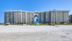 A large, multi-story hotel with a central arched entrance, located on a sandy beach. - Majestic Sun A912 | Beachfront Condo with Views! (Miramar Beach)
