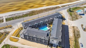 Eine Vogelperspektive auf ein Hotel mit Schwimmbad in Strandnähe und nahe einer Straße.