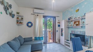 A living room with a sofa, a television, and a fireplace. - Holiday Home 'La Casa Del Bouganville' Near Beaches with Courtyard & Air Conditioning (Golfo Aranci)