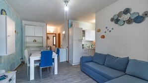 A compact living space with a dining area, kitchenette, and a sofa. - Holiday Home 'La Casa Del Bouganville' Near Beaches with Courtyard & Air Conditioning (Golfo Aranci)