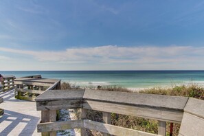 Ein hölzerner Steg führt zu einem Strand unter blauem Himmel.