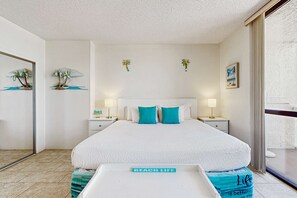 A hotel room with a large bed, two nightstands, a bedside table, a mirror, and a view of the sea through a sliding door.