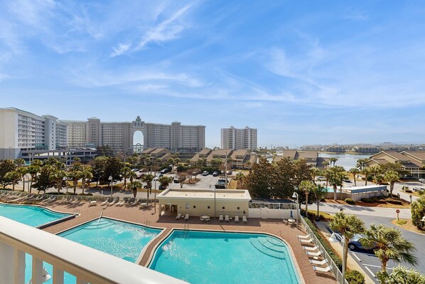 A resort with multiple swimming pools, a large building with an arched entrance, and a view of the surrounding area including other buildings and a body of water. - Fantastic & spacious coastal condo with a shared pool and on-site golf (Miramar Beach)