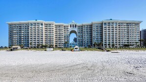 Een groot, meerhoog hotel met een centrale, gebogen entree, gelegen aan een zandstrand.
