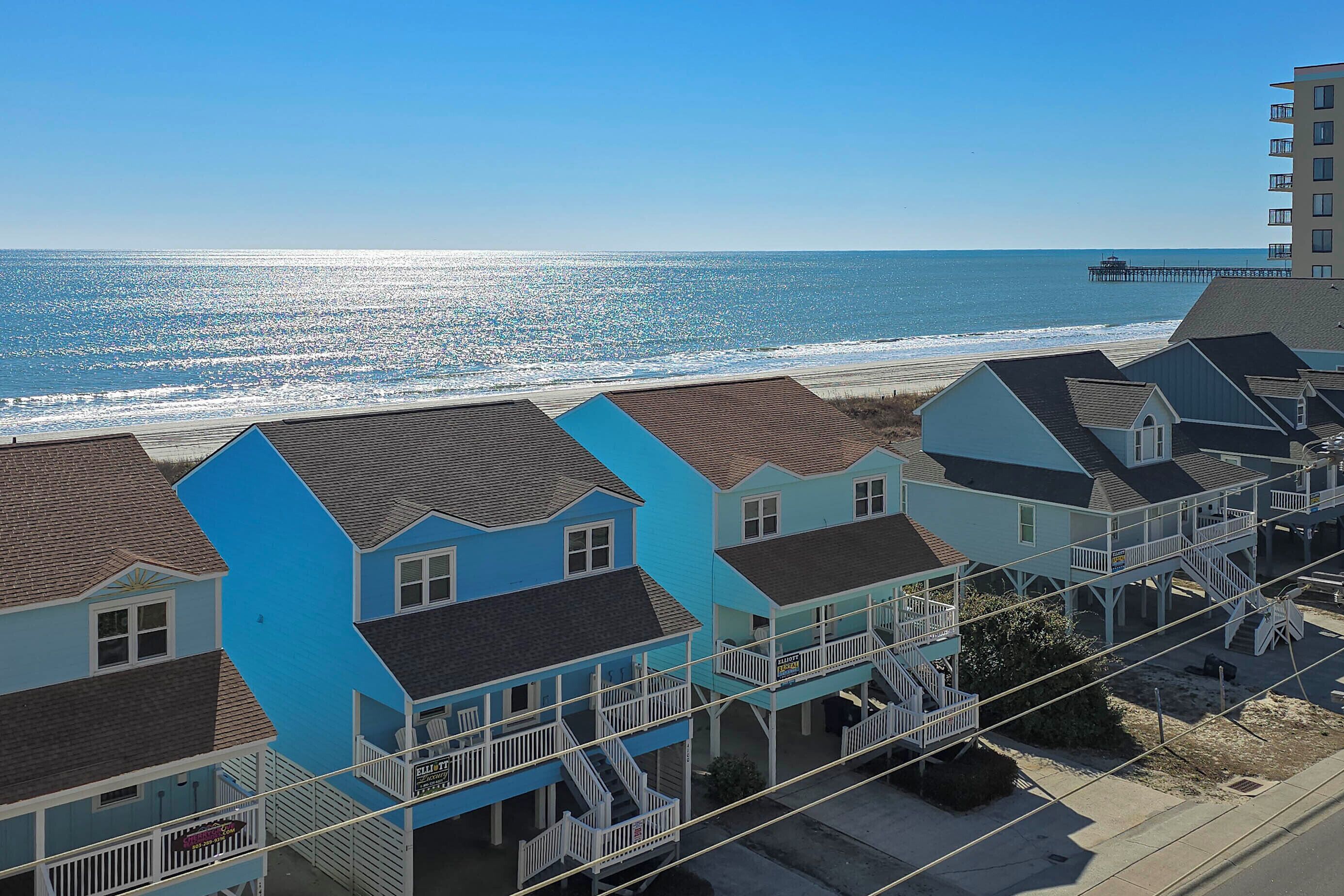 Un área residencial costera con casas que tienen balcones y un muelle que se adentra en el océano.