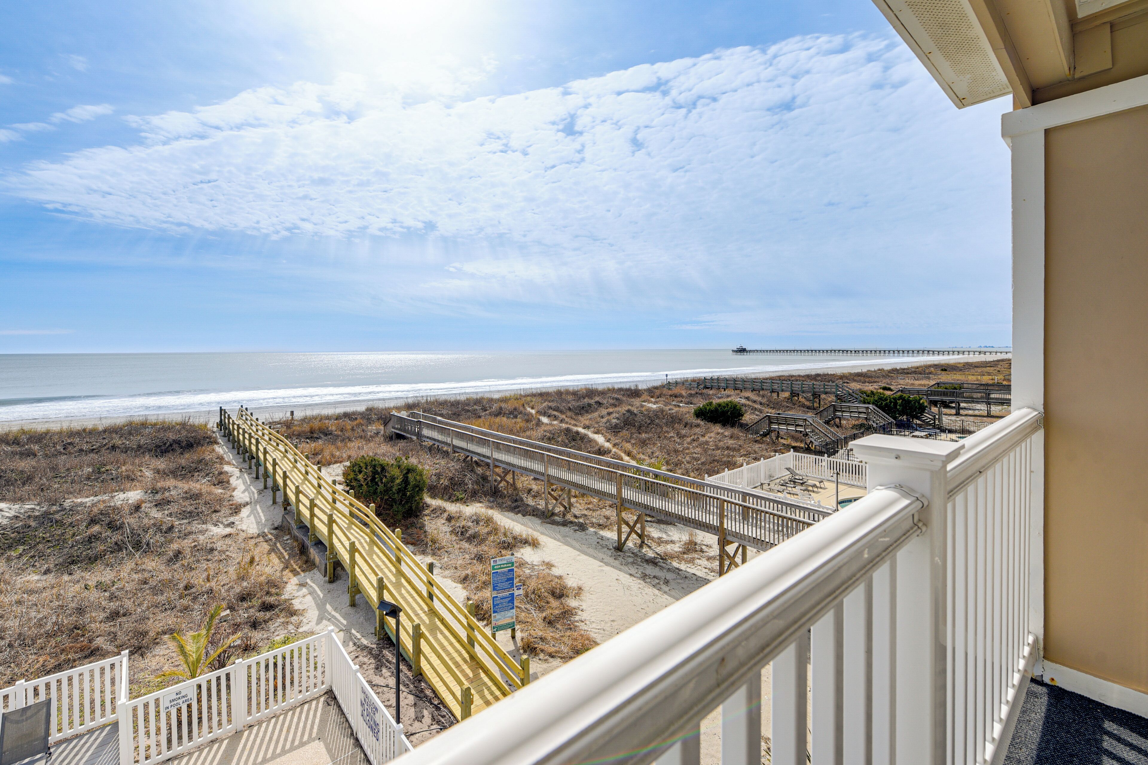 A balcony with a view of a beach and a pier.