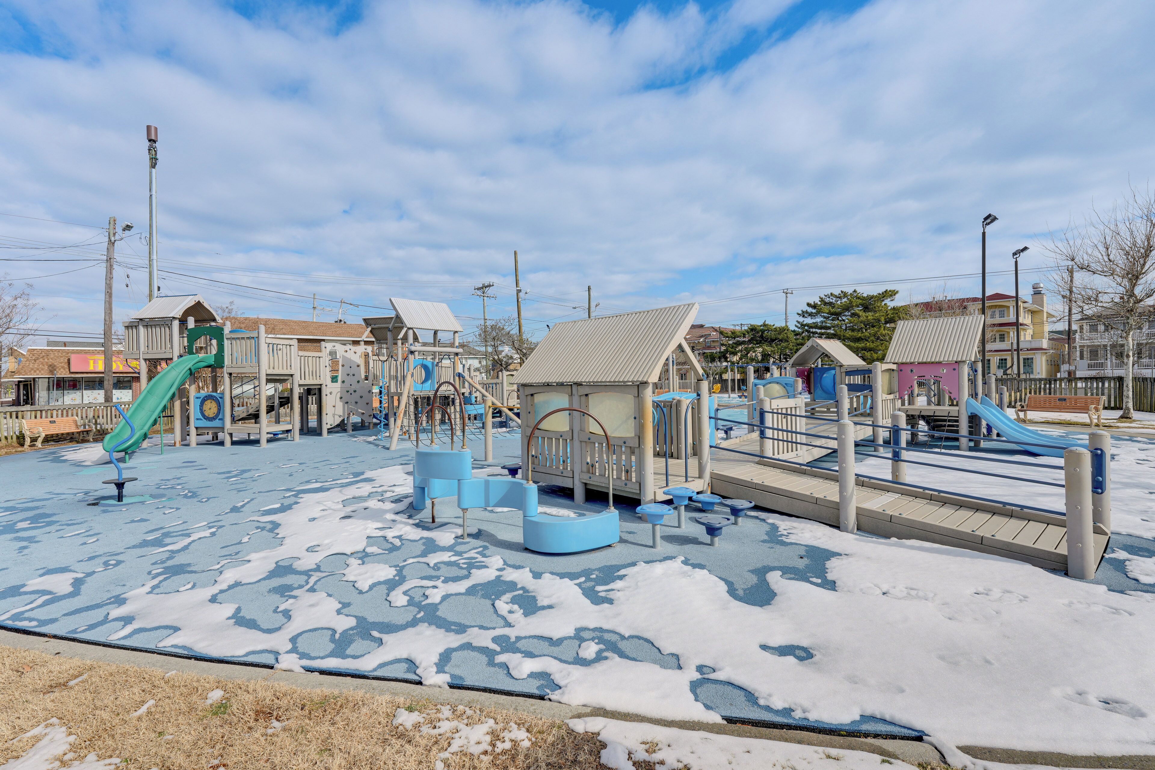 A playground with various play structures, including slides and climbing areas, surrounded by buildings.