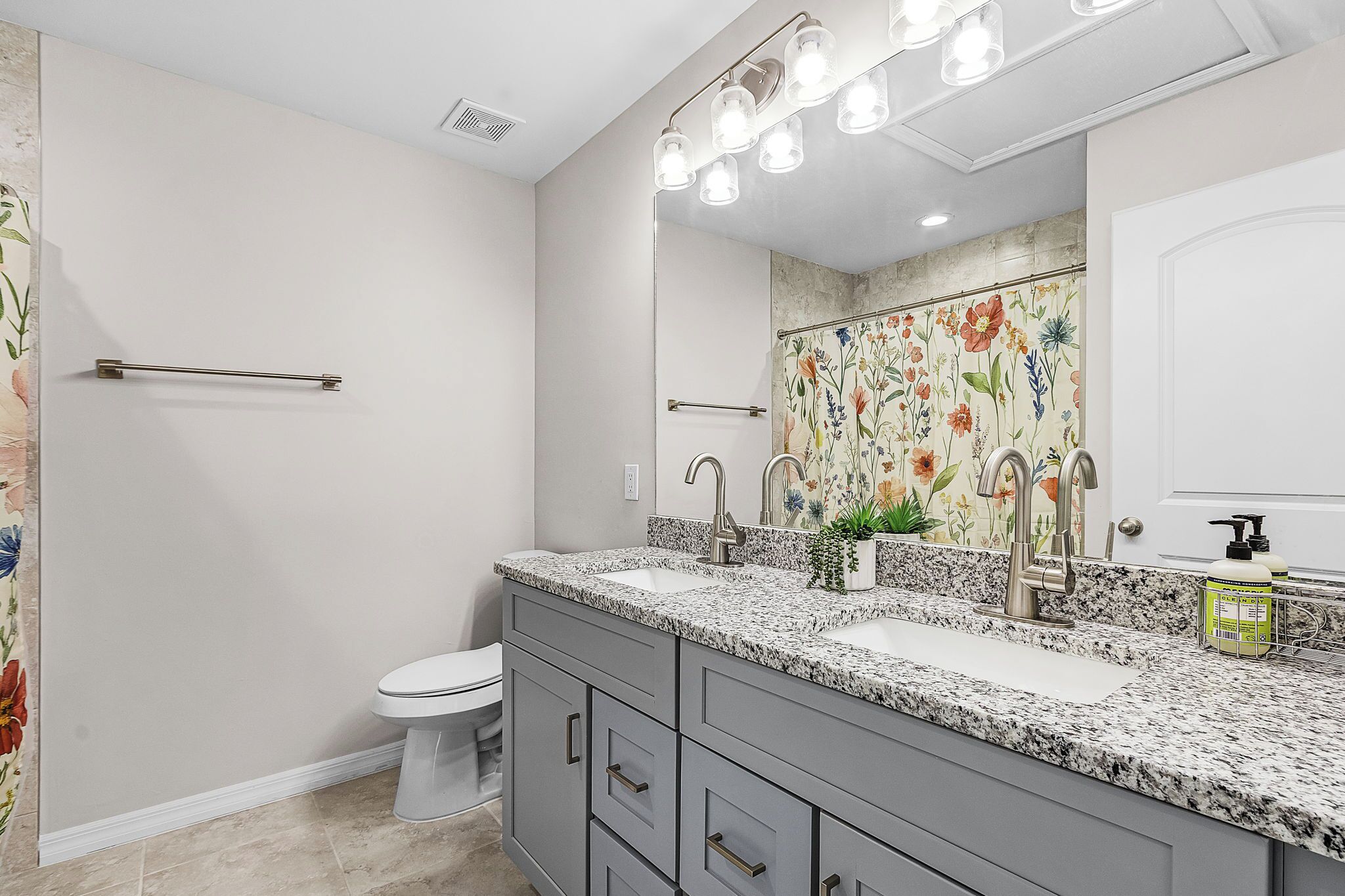 Une salle de bain avec un meuble-lavabo à deux vasques, des toilettes et un espace douche.