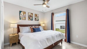 A bedroom with a bed, nightstand, ceiling fan, artwork, and a window with curtains. - Canal-front Fun! Fish & Relax in Cape Coral (Cape Coral)