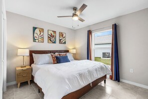A bedroom with a bed, nightstand, ceiling fan, artwork, and a window with curtains. - Canal-front Fun! Fish & Relax in Cape Coral (Cape Coral)