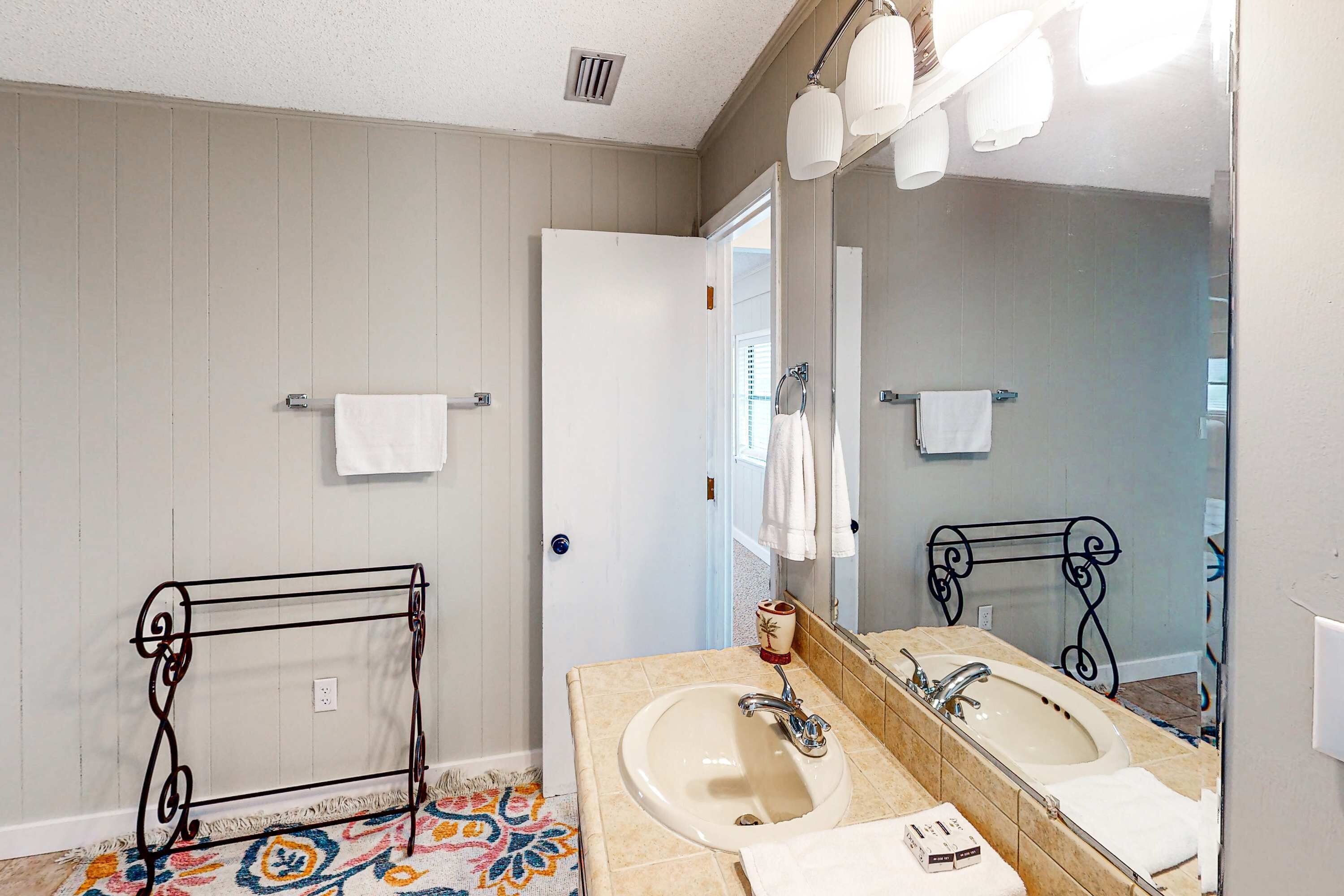 A bathroom with two sinks, a large mirror, and a towel rack.