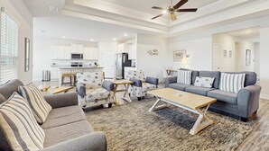A spacious living room with a gray sofa, patterned armchairs, a wooden coffee table, and a ceiling fan. - Spacious home steps from the beach with fast WiFi & washer/dryer (Port St. Joe)