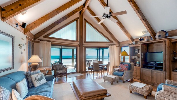 A spacious living room with high ceilings, large windows, and a view of the beach. - Snowbird-friendly beachfront home with a pool, tennis, washer/dryer, fireplace (St. George Island)
