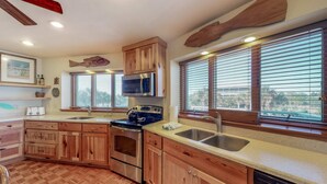 A kitchen with wooden cabinets, stainless steel appliances, a dishwasher, and large windows with blinds. - Snowbird-friendly beachfront home with a pool, tennis, washer/dryer, fireplace (St. George Island)