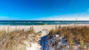 A sandy beach with a wooden pathway leading to the ocean, surrounded by tall grasses. - Snowbird-friendly beachfront home with a pool, tennis, washer/dryer, fireplace (St. George Island)