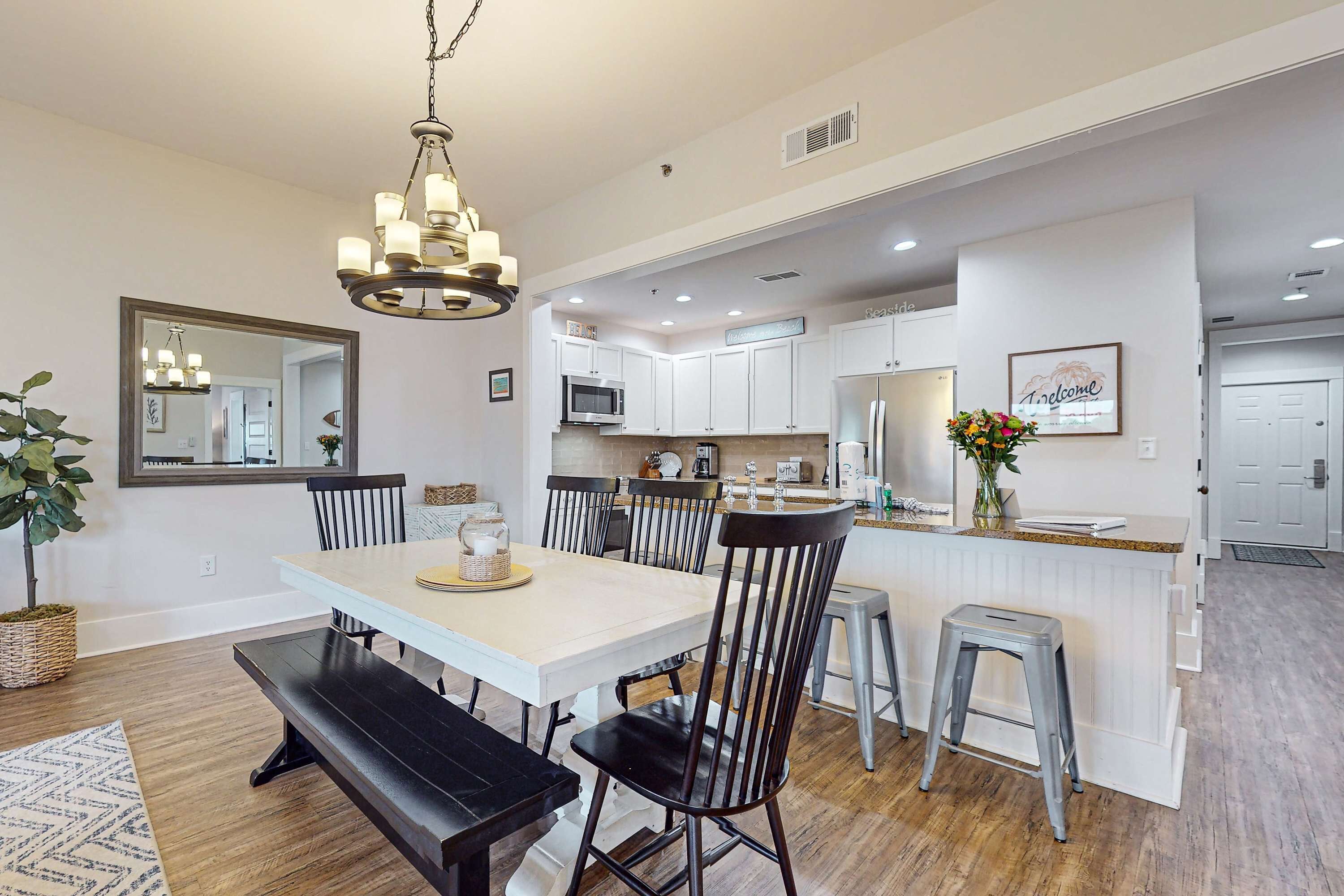 A modern kitchen with white cabinets, a stainless steel microwave, and a refrigerator.