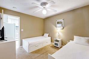 A bedroom with a single bed, a desk, a chair, a wardrobe, a ceiling fan, and a nightstand with a lamp. - Cozy beach condo with amazing views, beach access & on-site pool (Navarre Beach)