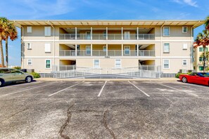A multi-story building with a parking lot in front. - Cozy beach condo with amazing views, beach access & on-site pool (Navarre Beach)