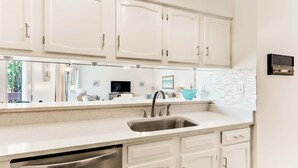 Una cocina moderna con armarios blancos, un lavamanos de acero inoxidable y un lavavajillas integrado.
