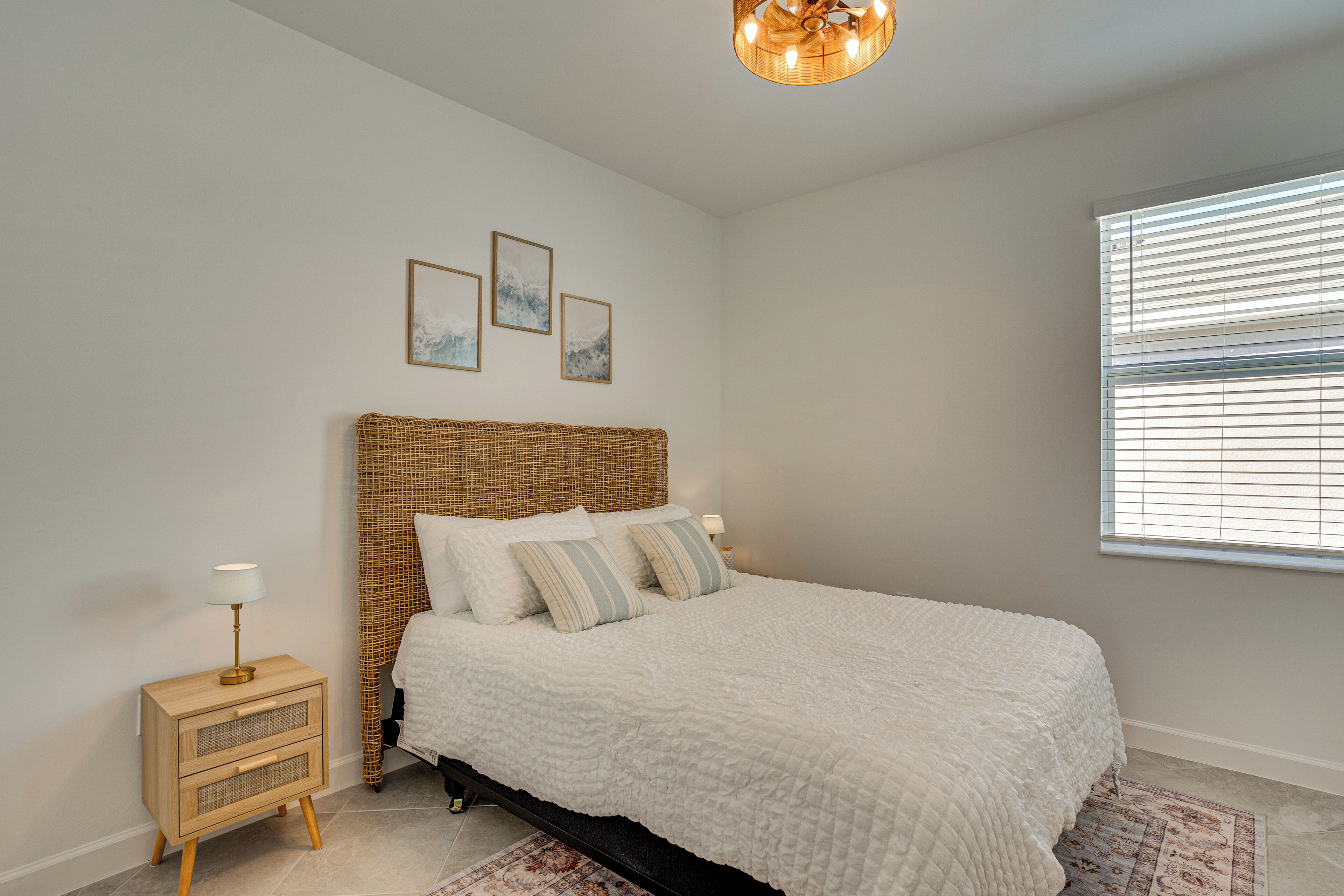 Ein Schlafzimmer mit einem großen Bett, einem Nachttisch, einer Lampe und drei gerahmten Bildern an der Wand.